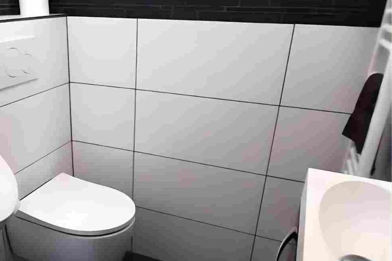 Badsanierung Köln Modernes Badezimmer mit Toilette, Waschbecken und hellen Fliesen.